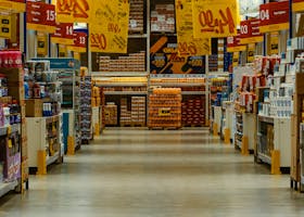Wide supermarket aisle with colorful sale banners and stocked shelves in a vibrant Brazilian store.
